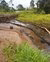Extraction pipe running through a small river surrounded by fields