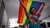 Person walking in front of a large group holding rainbow Pride flag above their head