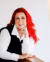 Portrait of Wendy van der Jagt, who has bright red hair, a button up white shirt with a vest.